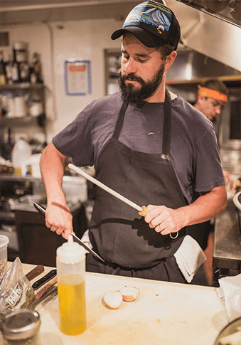 Dan Meiser in a kitchen cooking with knives