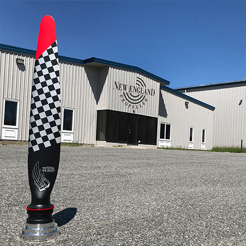 A black and white checkered propeller with red tip on the pavement outside of New England Propeller building in Windsor Locks, CT