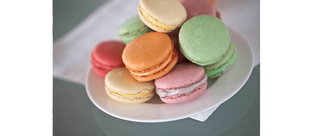 A small white plate piled with yellow, pink, red, orange, and green macarons